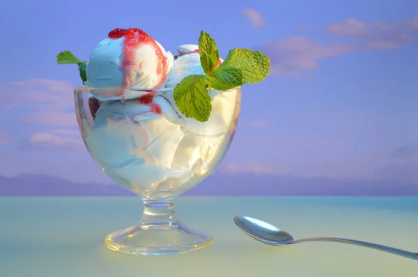 white ice cream with jam and mint leaves in a vase against the background of mountains and cloudy sky