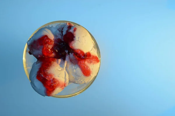 top view of white ice cream with red jam on a blue background