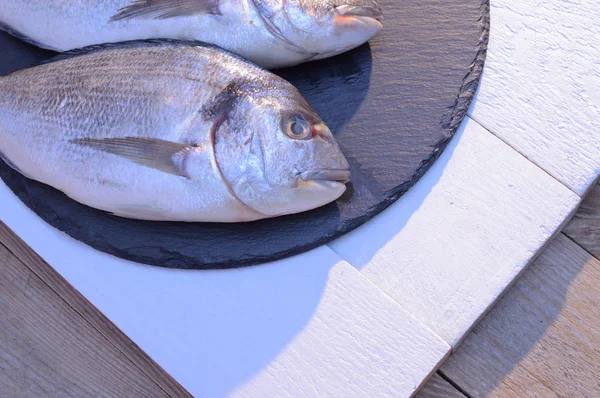 Две рыбы дорадо на черной тарелке — стоковое фото