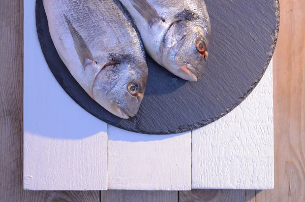 Две рыбы дорадо на черной тарелке — стоковое фото