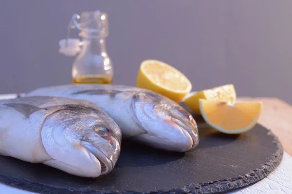 Dorado fish on a black plate with lemon — стоковое фото