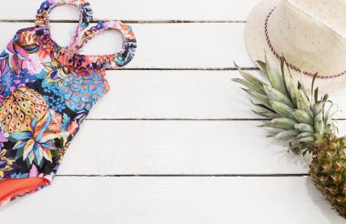 Hasır şapka, tropikal yazdırma mayo, ananas. Beyaz eski ahşap arka plan.