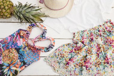 Kızlar elbise kolaj. Hasır şapka çiçek elbise, ananas, tropikal yazdırma mayo. Beyaz eski ahşap arka plan.