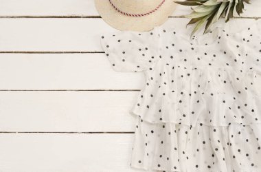 Kadın gömlek, hasır şapka, ananas. Beyaz ahşap zemin.