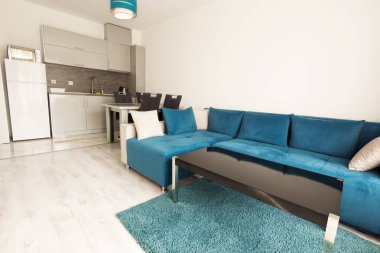 Modern aydınlık ve rahat oturma odası kanepe, yemek masası ve mutfak dekorasyon. Gri ve turkuaz mavi stüdyo daire.
