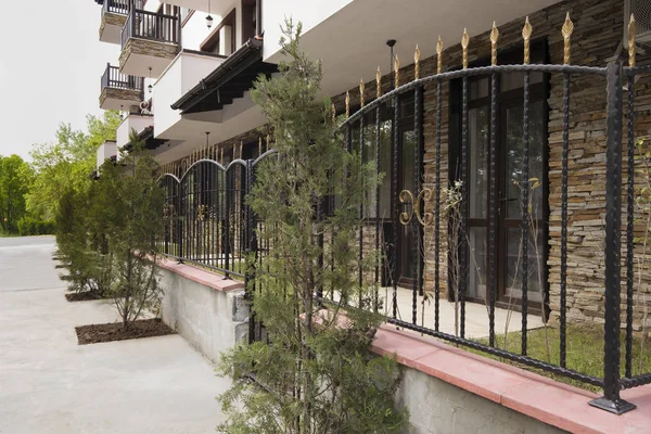 Ferforje çit. Modern binanın dış bahçede. Modern bir apartman cephe. Taş döşeme cephe ile tatil kompleksi otel binası.