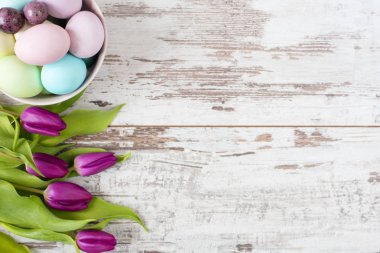 Paskalya yumurtaları Pastel renkli. Bu güzel bahar çiçekleri - mor laleler hafif bir rustik ahşap arka plan üzerinde. Çerçeve çiçek çiçekler çarpıcı. Kopya alanı