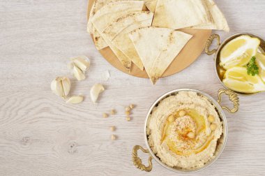 Ev yapımı humus zeytinyağı üzerinde hafif bir arka plan ile. Bir ahşap tahta üzerinde Arapça ekmek