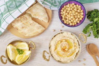 Ev yapımı humus zeytinyağı üzerinde hafif bir arka plan ile. Arapça ekmek, nohut ve limon çevresinde