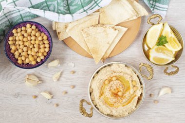 Ev yapımı humus zeytinyağı üzerinde hafif bir arka plan ile. Arapça ekmek, nohut ve limon çevresinde