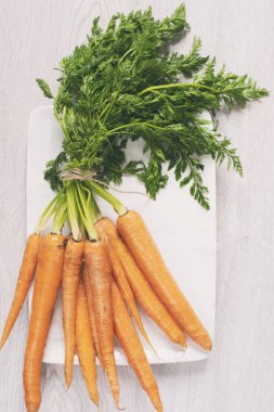 Taze havuç hafif gri ahşap zemin üzerine yeşil yaprakları ile. Mat filtre eklendi