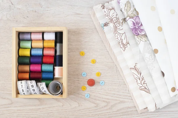 Composición con hilos de coser, telas y accesorios sobre fondo de madera, vista superior —  Fotos de Stock