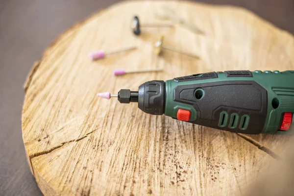 Drill rotary tool with accessories, Dremel tool heads. Multi tool on wooden table in jeweler workshop. Close up of a screwdriver with sander cone drill bit — Stock Photo, Image