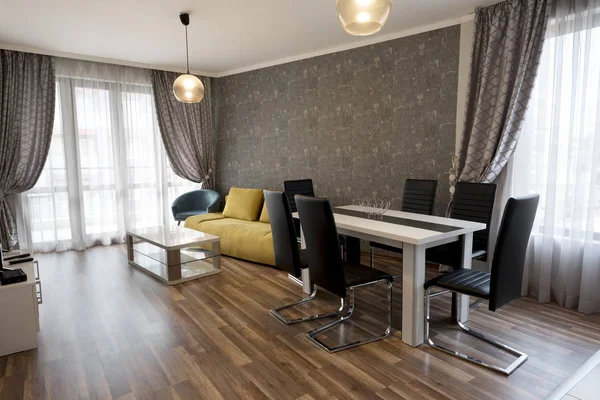 Nueva sala de estar moderna. Nueva casa. Fotografía interior. Suelo de madera. Mesa de comedor con juego de sillas, sofá amarillo — Foto de Stock