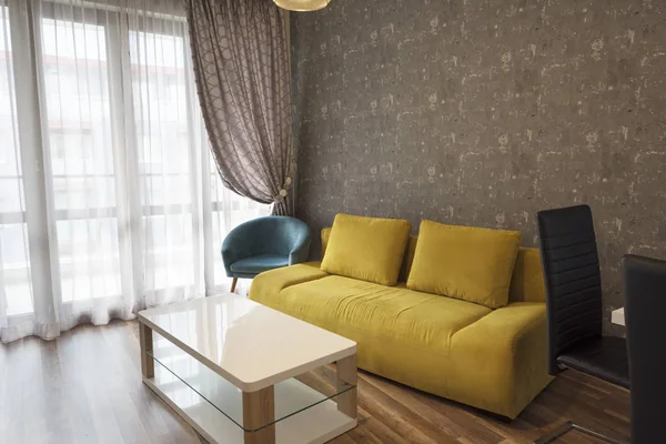 Nueva sala de estar moderna. Sofá amarillo cerca de la ventana. Nueva casa. Fotografía interior. Suelo de madera —  Fotos de Stock