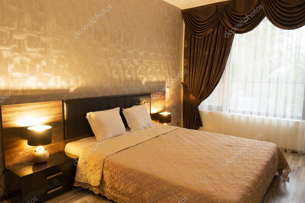 Classy bedroom interior design. Large bed. Room with brown color tone furniture. Windows with long curtains, drapery and sheers. Interior photography