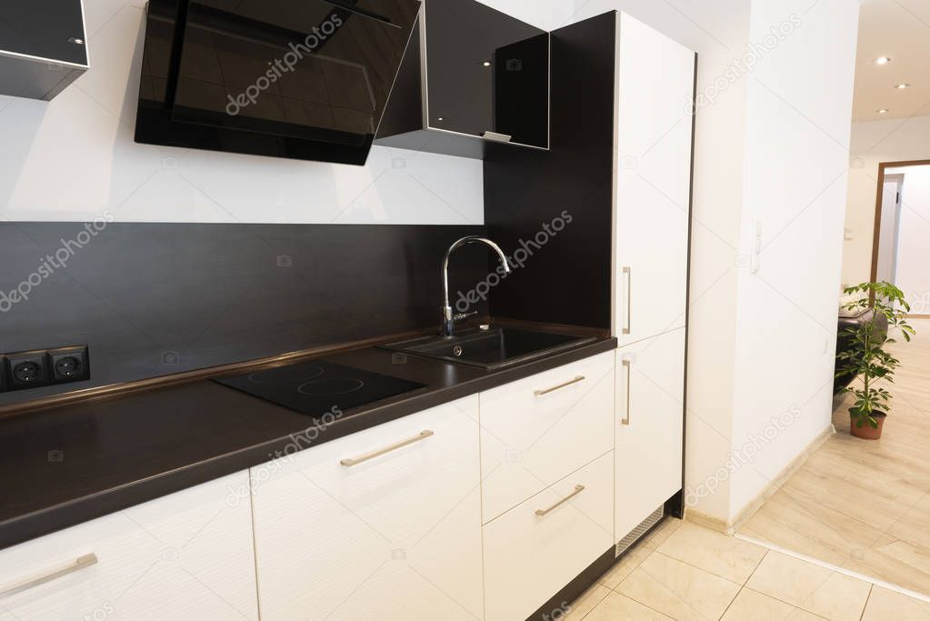 Modern new light interior of kitchen with white and black furniture