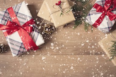 Noel geçmişi. El Sanatları ve Kırmızı Çizgili Kağıt Dal, Keten Kordon, Ahşap Masa Üzerinde Kırmızı Yay ile süslenmiş Noel Kutuları Top View. Çizilmiş Kar. Kopyalama Alanı