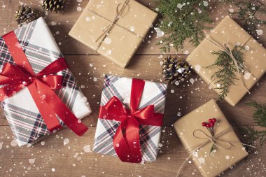 Noel geçmişi. Noel Kutuları ve Işıklar Üst Görünümü Zanaat ve Kırmızı Çizgili Kağıt Dal, Keten Kordon, Ahşap Masa Üzerinde Kırmızı Yay ile süslenmiş. Çizilmiş Kar