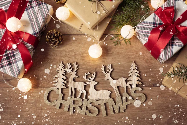 Καλά Χριστουγεννιάτικη επιγραφή, έλατο, φιγούρες από στολίδια και εορταστικά κουτιά δώρων. Χειμερινές διακοπές και καλή ιδέα για το νέο έτος. Επίπεδη διάταξη χριστουγεννιάτικων αξεσουάρ και φώτων — Φωτογραφία Αρχείου