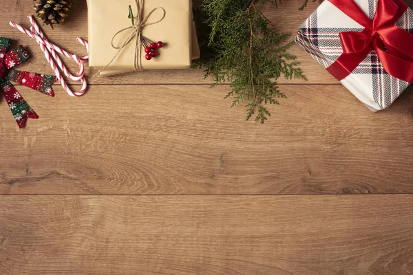 Fondo de Navidad. Vista superior de las cajas de Navidad en papel artesanal y de rayas rojas decoradas con rama, cable de lino, arco rojo en mesa de madera Imágenes De Stock Sin Royalties Gratis