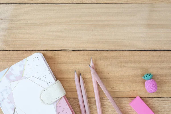 Vista superior del escritorio de la oficina con el cuaderno y los lápices en fondo de madera. Freelance Fashion Cómodo espacio de trabajo de feminidad en posición plana. Vista superior, rosa y blanco. Copiar espacio —  Fotos de Stock