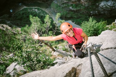 Young happy woman who is climbing along a via ferrata clipart