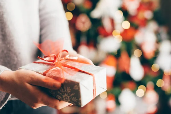 Fechar Vista Das Mãos Mulher Segurando Presente Natal Fundo Árvore — Fotografia de Stock