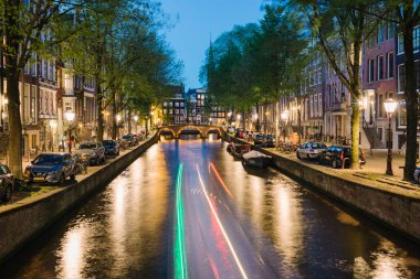 Amsterdam, Hollanda-Mayıs 14, 2019: bir kanal üzerinde bir tekne ve gece görünümü ışık parkurları