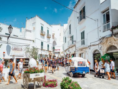 Ostuni, Puglia İtalya - 23 Ağustos 2019 Cuma: Güneşli bir günde Ostuni şehrinin sokaklarında yürüyen insanlar