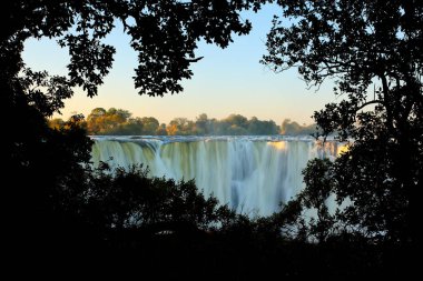 Victoria Falls, waterfall in southern Africa on the Zambezi River at the border between Zambia and Zimbabwe. Landscape in Africa. A lot of water durring summer season. Aperture in green forest vegetation. clipart