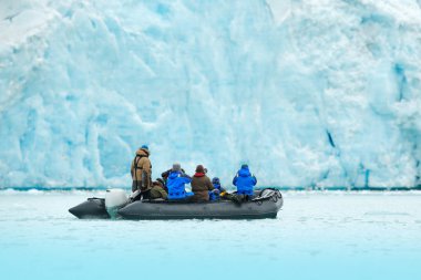 Doğa severler Arctic Svalbard, Norveç'te. Motorlu tekne turist buzul ile Buz Denizi. Kuzey kutup cruise kışın, fotoğrafçılar ile siyah powerboat arka planda karlı buzkıran.