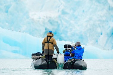 Doğa severler Arctic Svalbard, Norveç'te. Motorlu tekne turist arka planda buz deniz, karlı dağda. Kış, fotoğrafçılar ile siyah powerboat nde Arctic yolculuk.