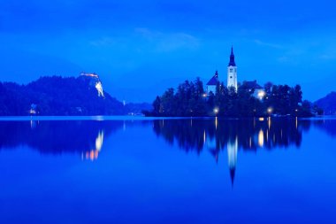 Sonbahar manzarası göl kenarında. Yeşil ağaç ön planda yaprak. Alacakaranlık akşam Bled, Slovenya, ışık. Göl Adası, St Martin Katolik Kilisesi ve kale Sıradağları, Slovenya, Avrupa ile. 