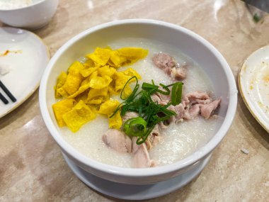 Sıcak ve rahatlatıcı bir kase leziz tavuk pirinçli yulaf lapası gevrek şeritler ve taze otlarla kaplı.