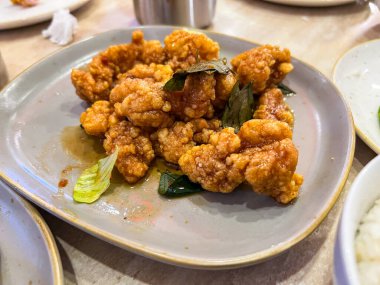 Bu yemek, taze bitkilerle süslenmiş bal soslu çıtır kızarmış tavuk ve zarif bir şekilde servis edilmiş çeşitli sebzeler içeriyor.