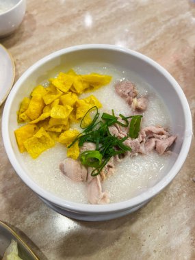 Sıcak ve rahatlatıcı bir kase leziz tavuk pirinçli yulaf lapası gevrek şeritler ve taze otlarla kaplı.