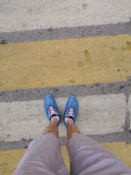 Legs men in shorts and sneakers in Shoe covers at the crosswalk