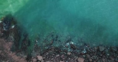 Dalgaların yukarıdan görünüşü mavi bir okyanusta kayalara çarpıyor. Deniz dalgaları güzel sahil manzaralı hava aracı 4K 'da. Kuş bakışı okyanus dalgalarının yukarıdan kayalıklara çarpması.. 