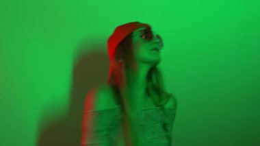 Kadın neşeyle dans ediyor ve ışıklar ve spot ışıkları altında dans ediyor. Neon renkleri ve çılgın kadın dans edip şarkı söylüyor.   