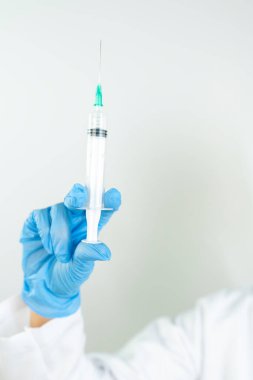 Sıvı aşılarla dolu bir şırıngayı laboratuvarda tutan doktor ya da bilim adamı olan Covid-19 Corona virüsüne karşı kavramsal mücadele: hastalıklar, tıbbi bakım, bilim.   