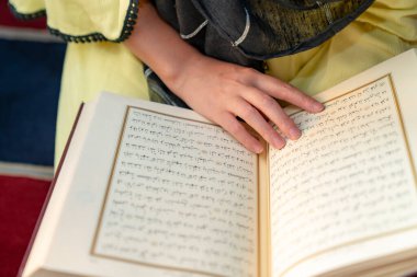 Camide Kuran 'ı tutan başörtüsü ve tesettürlü güzel Müslüman kadın portresi. Din kavramı.