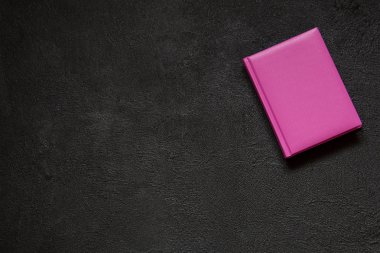 Siyah bir beton zemin üzerine pembe Not defteri. Soyut çimento arka planda vintage tarzı. Üstten görünüm.