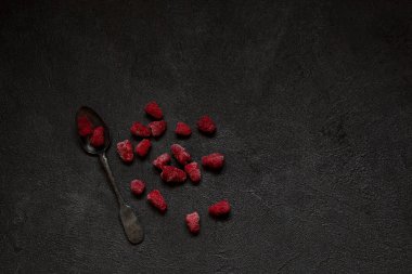 Ahududu üzerinde kopya alanı metin veya yazıt için siyah beton zemin üzerine Gümüş antika kaşık çilek donmuş. Sağlıklı gıda fikir. Üstten görünüm.