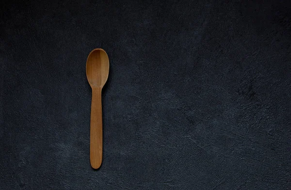 wooden spoon on a black concrete table. Vintage style. Top view.