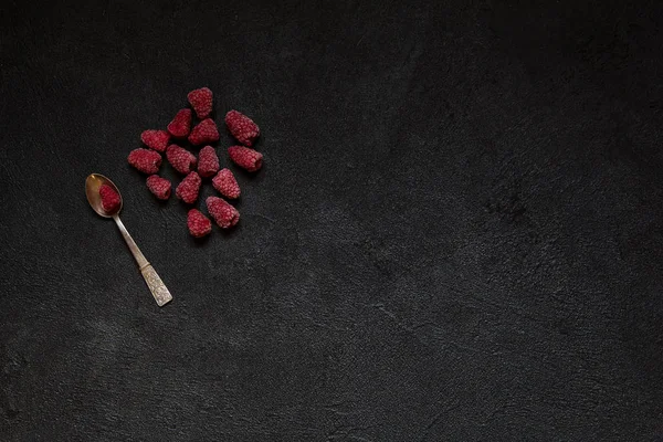 Gümüş kaşık siyah beton zemin üzerine ahududu meyveleri donmuş, metin veya yazıt için alan kopyalayın. Sağlıklı gıda fikir. Üstten görünüm.