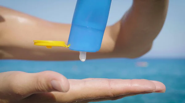 Ragazza Tiene Crema Solare Sulle Mani Sul Mare Bottiglia Blu — Foto Stock