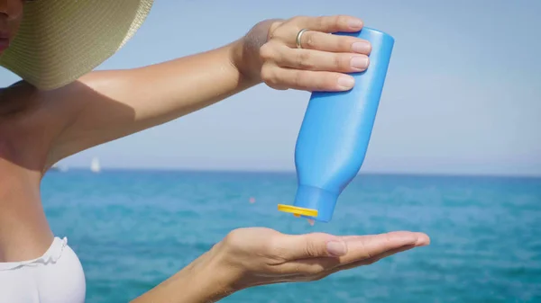 Flickan Håller Solskydd Grädde Händerna Havet Blå Flaska Bakgrund Blå — Stockfoto
