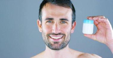 mutlu yakışıklı adam kameraya bakarak ve krem kavanoz tutan anız ile gülümseyen