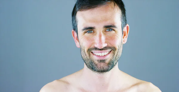 smiling happy handsome man with stubble posing on camera against grey background